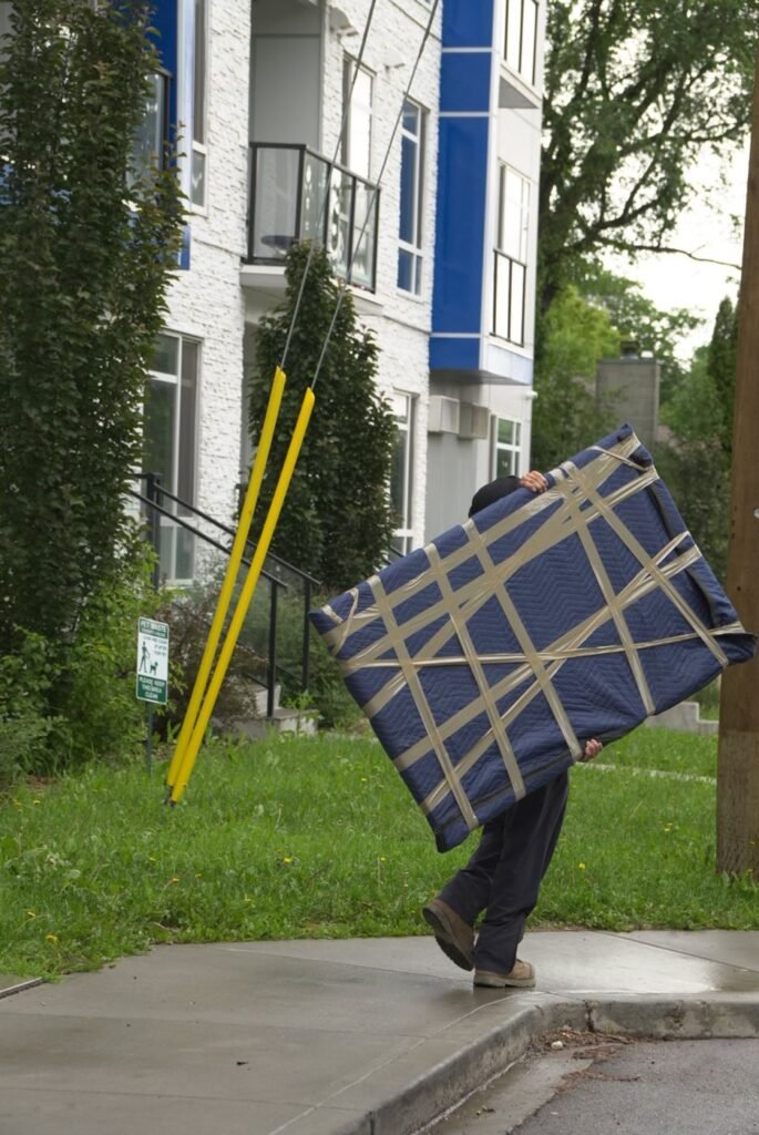 Mover carrying a blanket-padded mattress in Edmonton