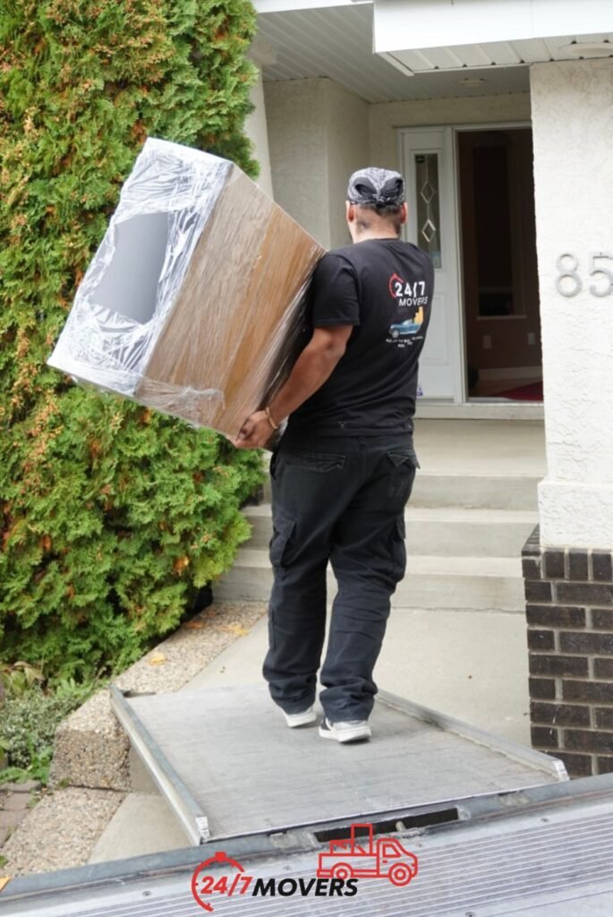 Mover carrying shrink-wrapped furniture up a truck ramp in Edmonton
