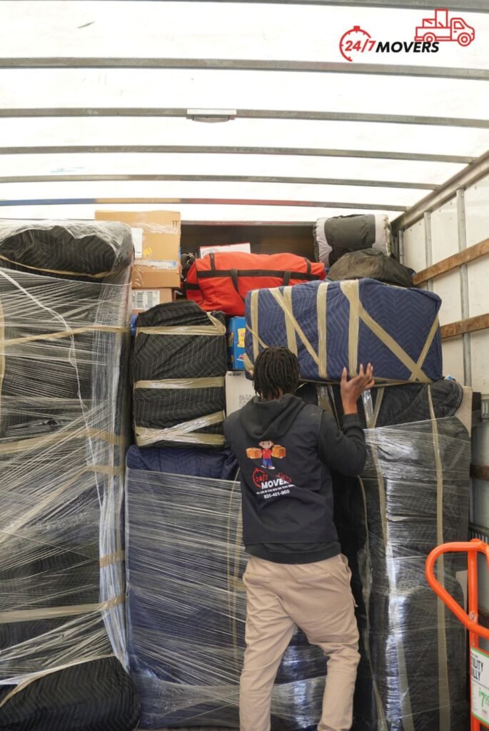 Mover stacking blanket-wrapped furniture inside a moving truck