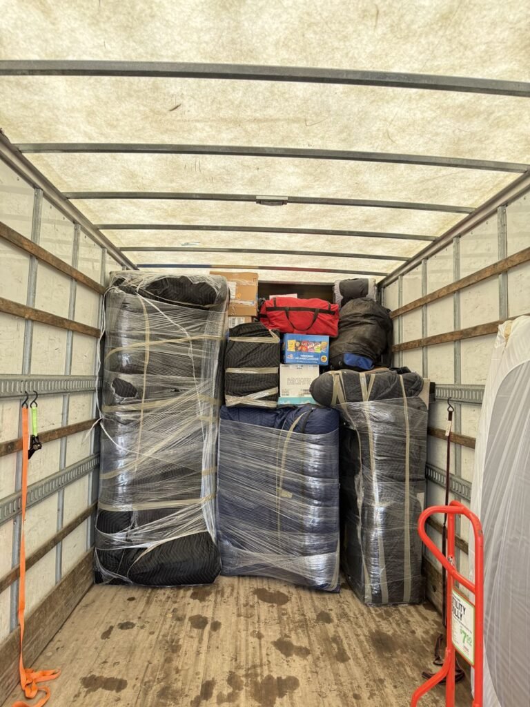 Moving truck loaded with blanket- and shrink-wrapped furniture
